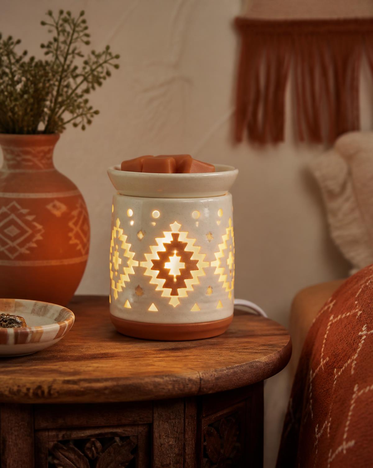 A ceramic wax warmer glowing on a rustic side table